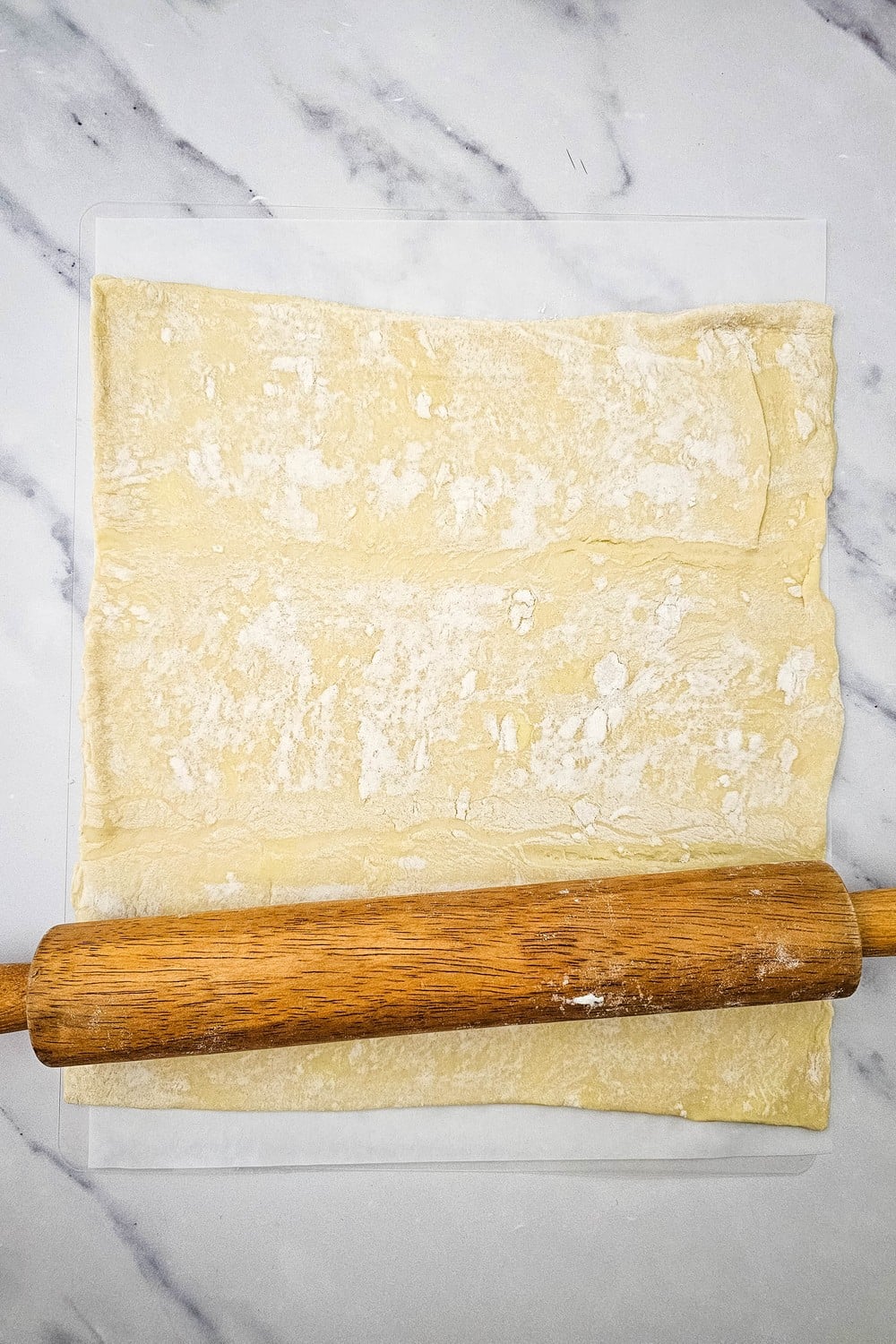 Rolling puff pastry sheet into a square with a rolling pin