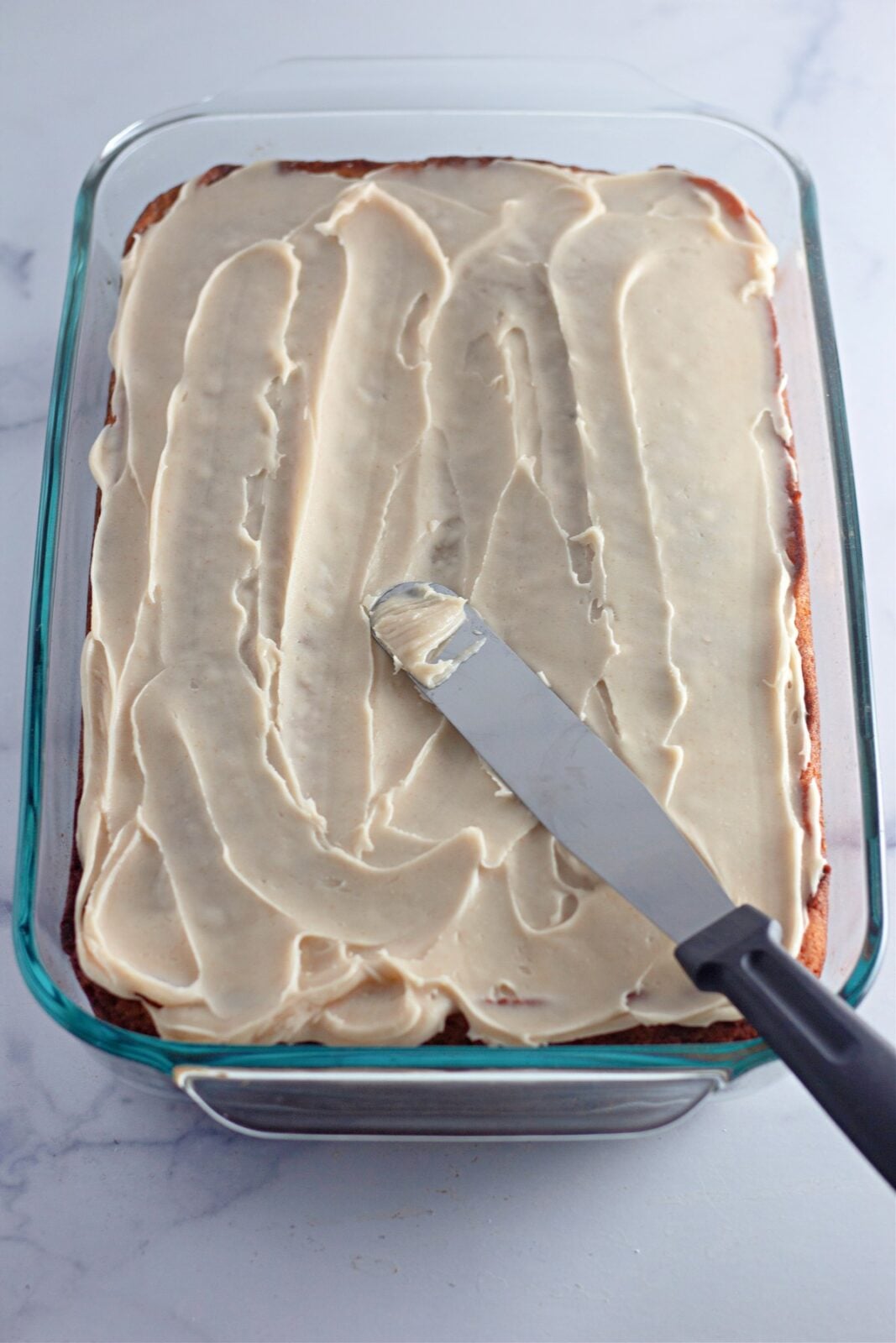 Banana coffee cake in a glass 9x13 pan spread with browned butter frosting