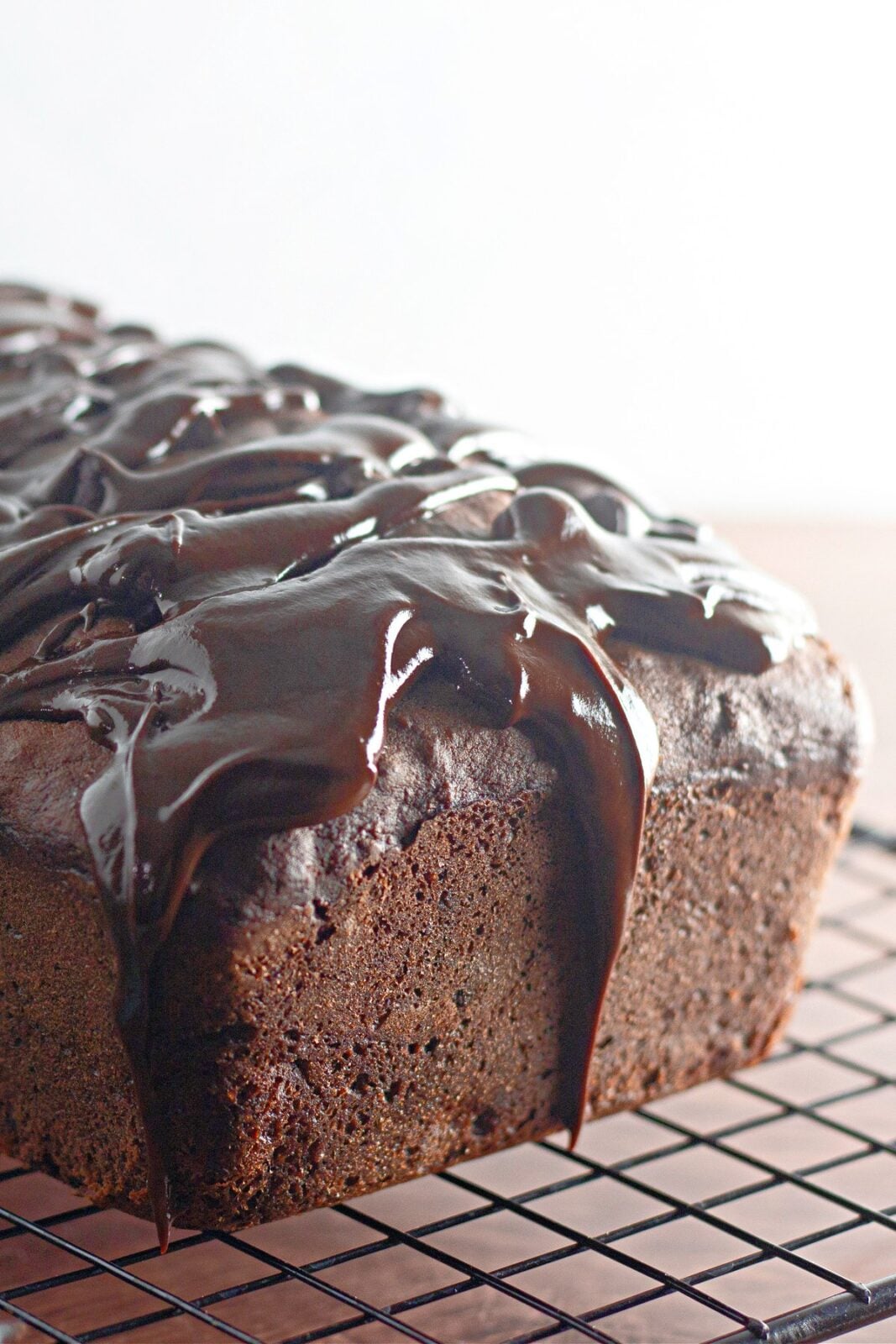 Fudge frosted chocolate banana bread loaf on a wire cooling rack
