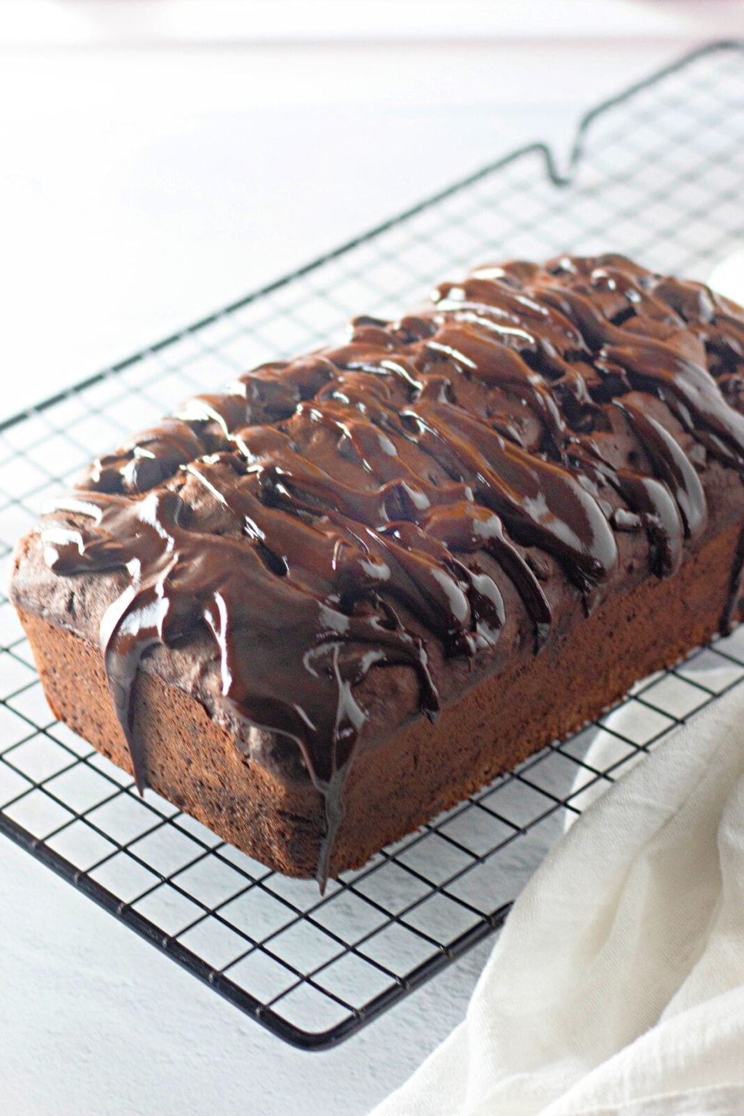 Whole glazed chocolate banana bread loaf on a black wire rack