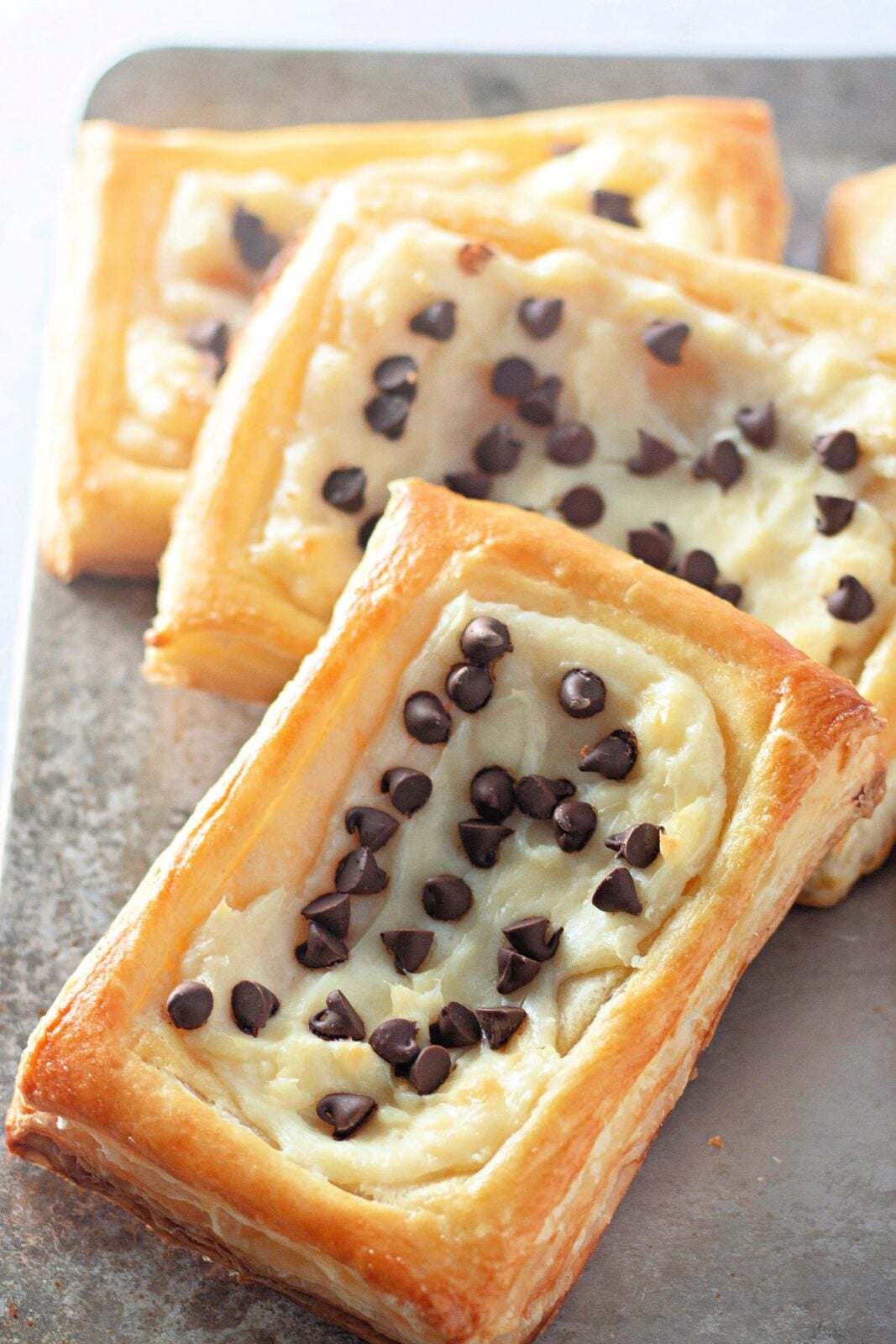 Chocolate chip cream cheese danishes stacked on a metal tray