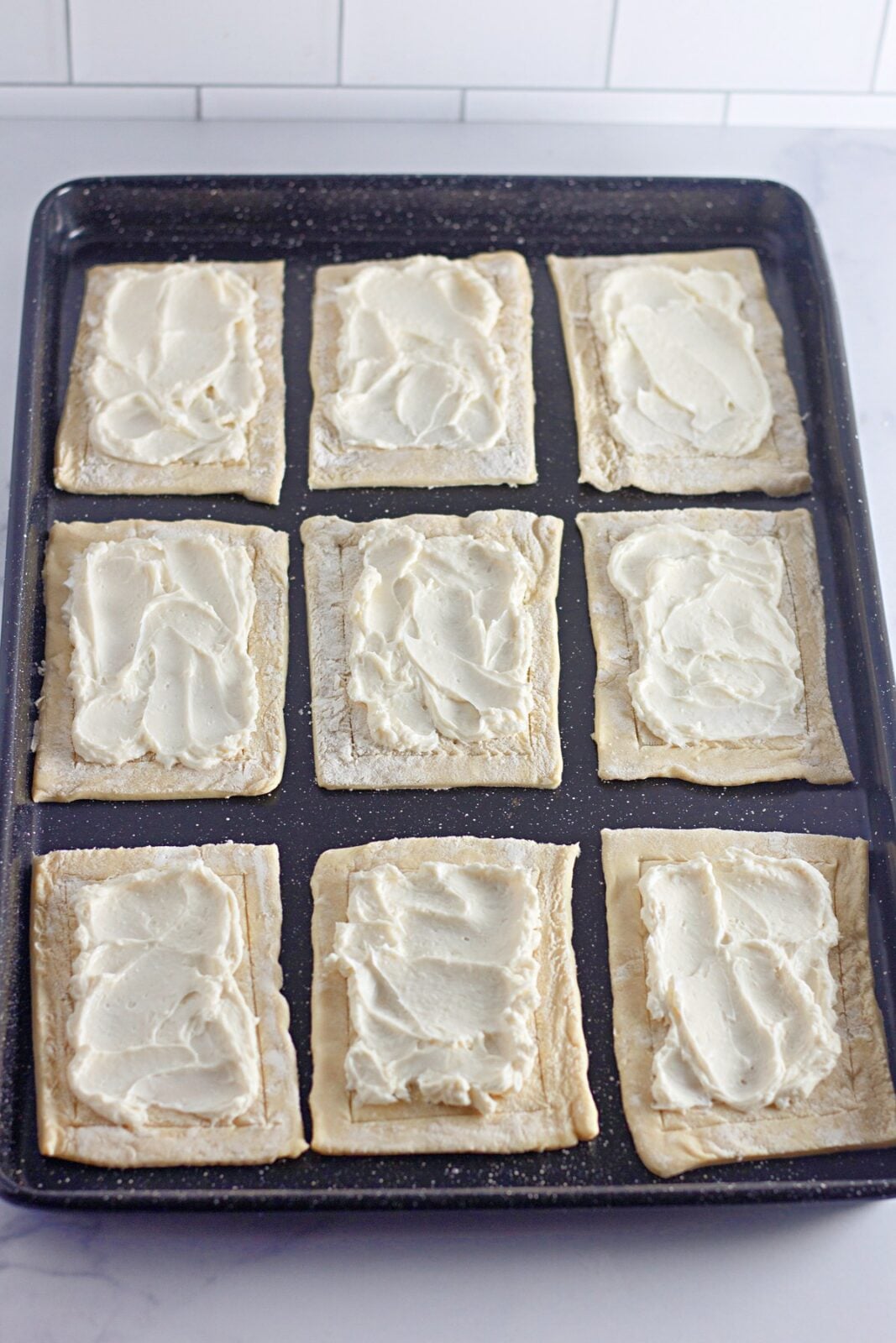 Sweetened cream cheese filling spread inside the borders of each pastry rectangle