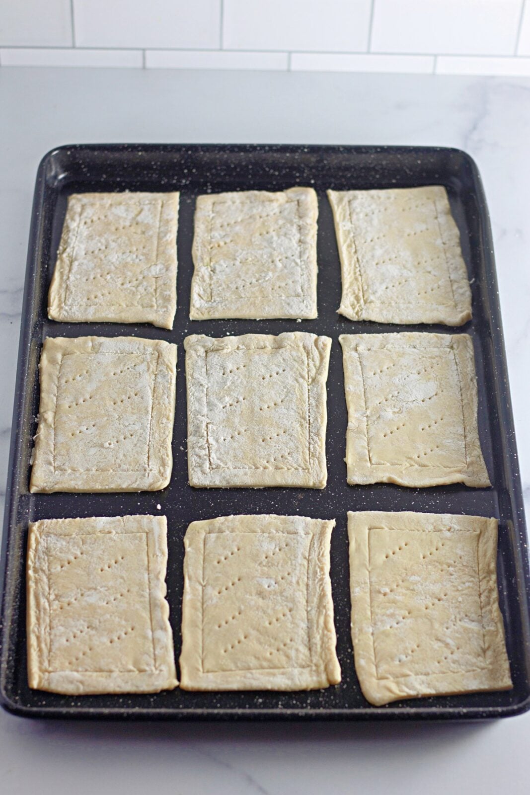 Pastry rectangles with scored borders and fork-docked centers on the baking sheet