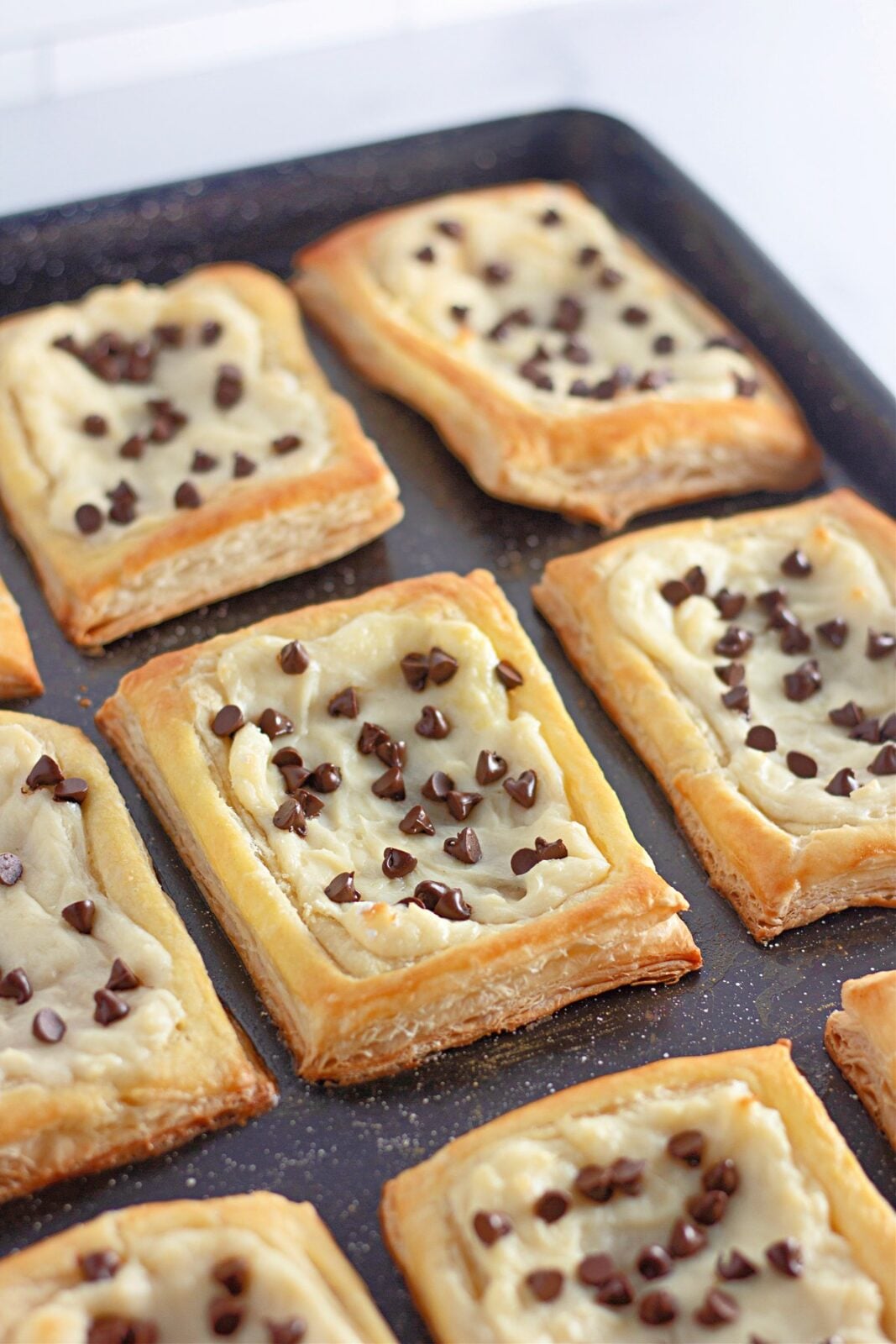 Baked chocolate chip cream cheese danishes with golden puffed borders on the baking sheet