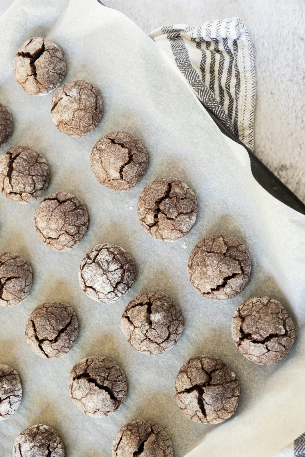 Baked chocolate snowball cookies with cracked powdered sugar tops on a tray