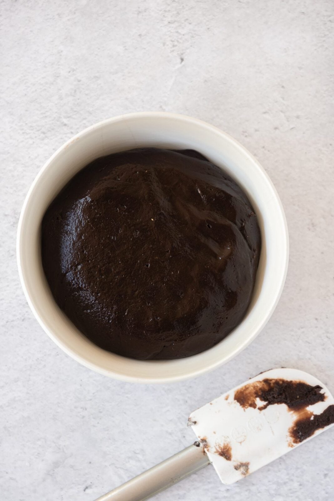 Smooth chocolate cookie dough in a white bowl with a spatula