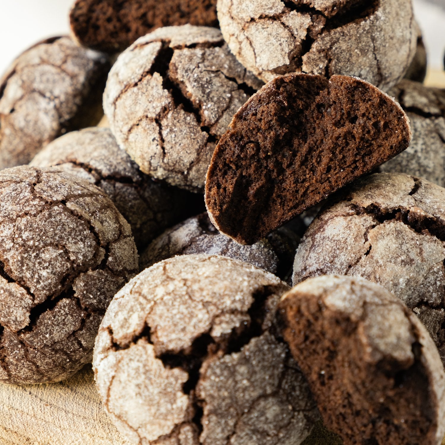 Chocolate snowball cookies stacked with a broken cookie showing the fudgy center