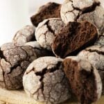 Chocolate snowball cookies on a wooden board with a halved cookie on top