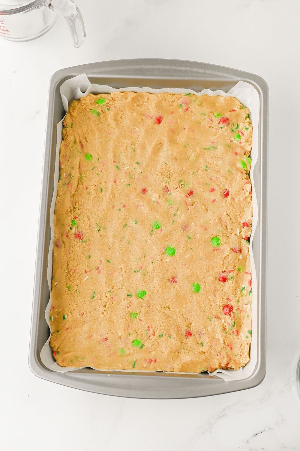 Christmas cookie bar dough pressed into a parchment lined 9x13 pan