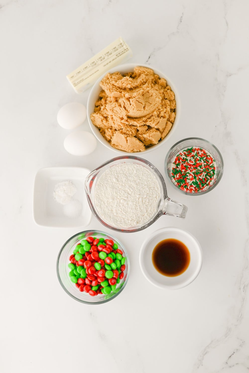 Ingredients for Christmas cookie bars: butter, brown sugar, eggs, flour, holiday M&Ms and sprinkles