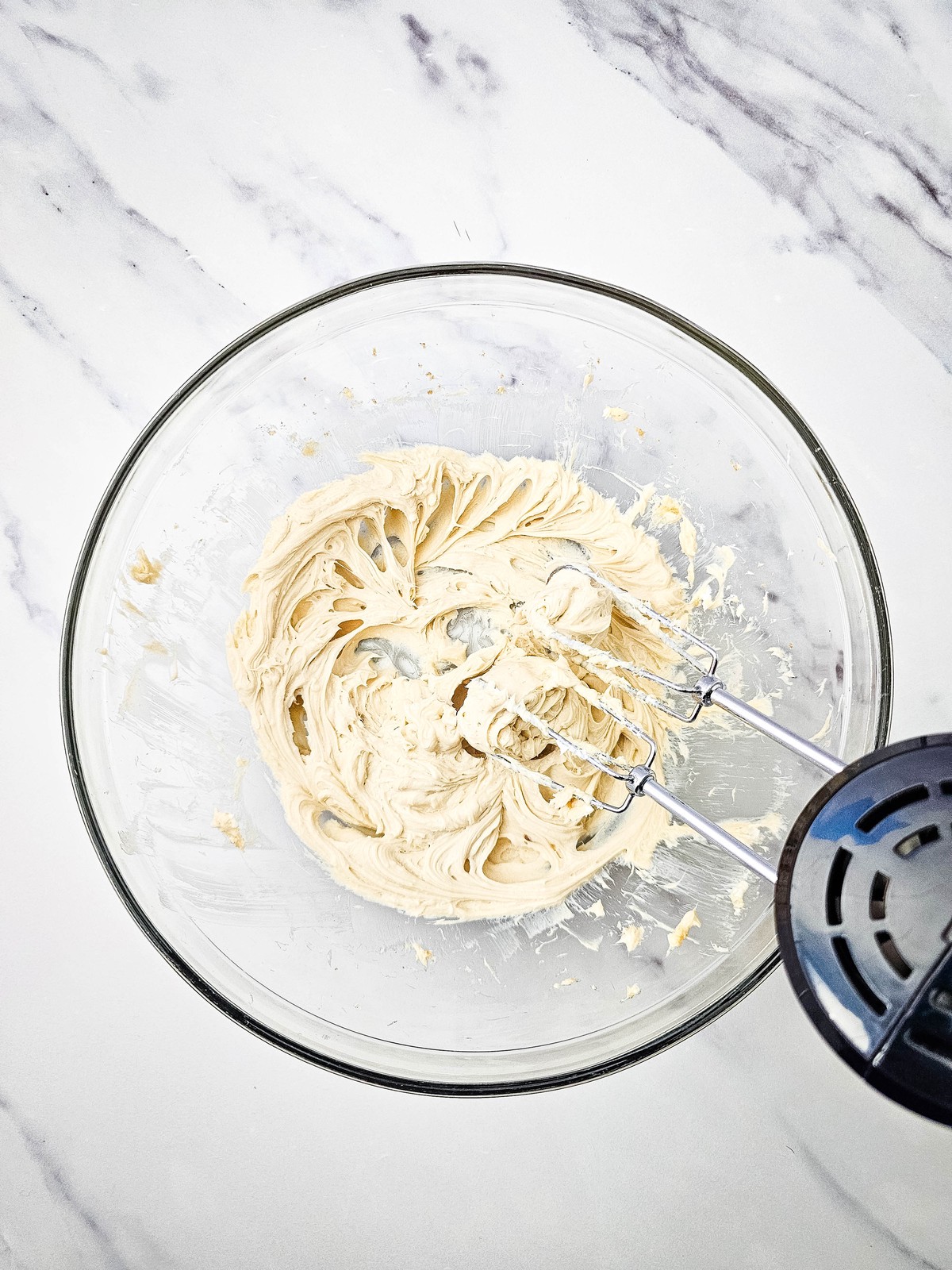 Cream cheese and brown sugar beaten smooth in a glass bowl with an electric mixer