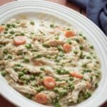 Creamy crockpot chicken casserole with peas and carrots on a white plate