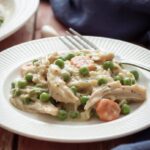 A serving of creamy crockpot chicken casserole with peas and carrots and a fork