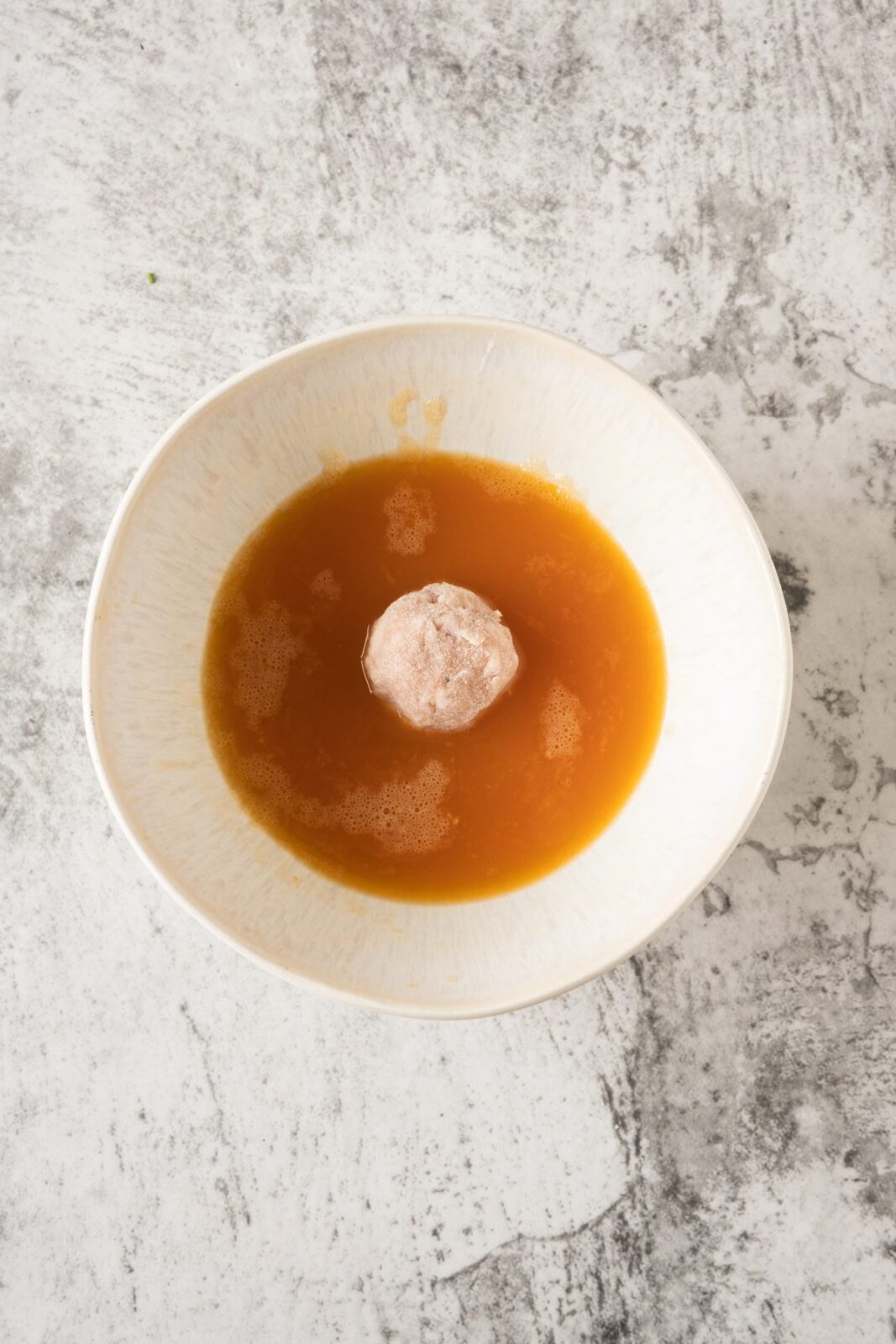 Dipping a chicken ball into egg wash