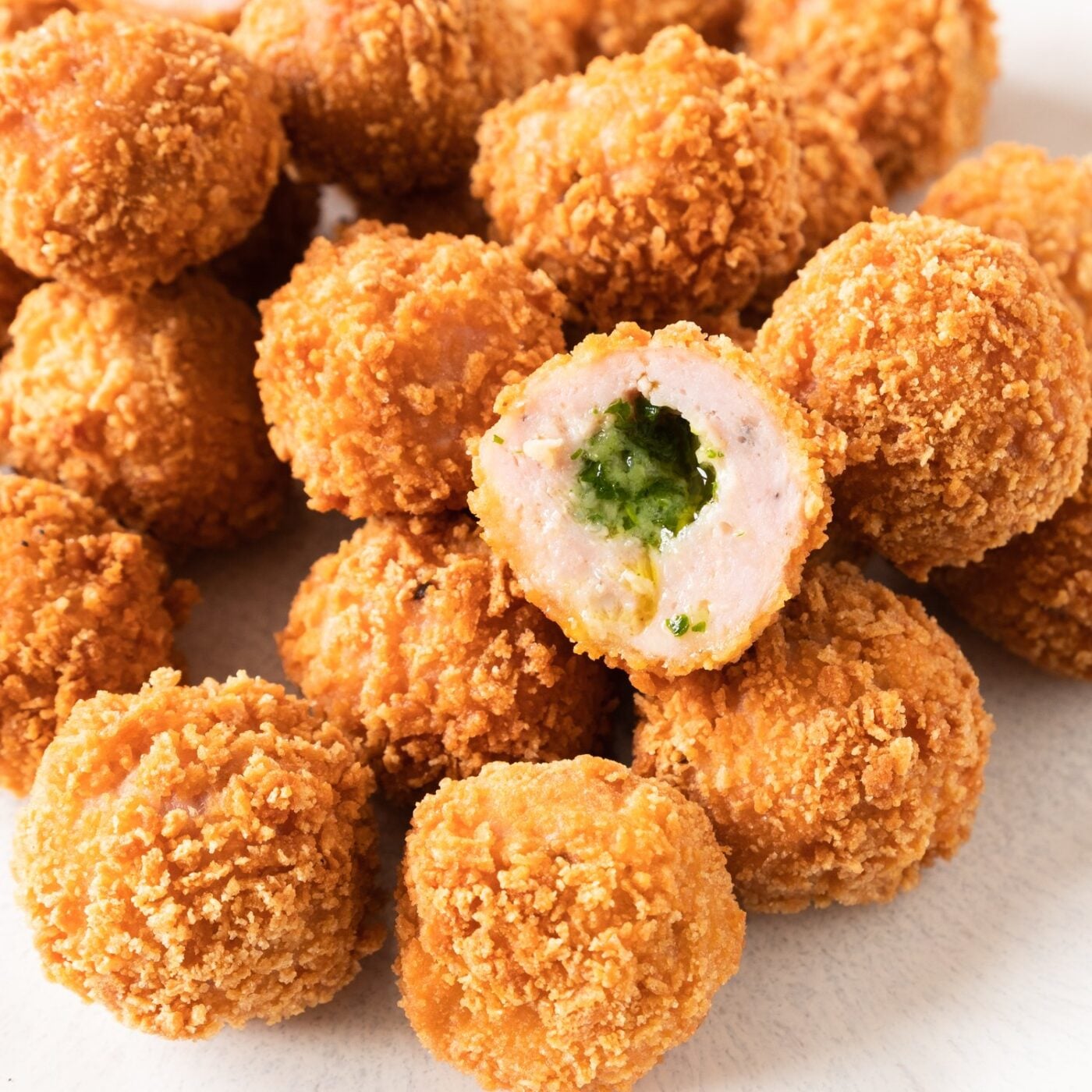Crispy garlic butter chicken balls piled up with one cut open showing the herbed butter center