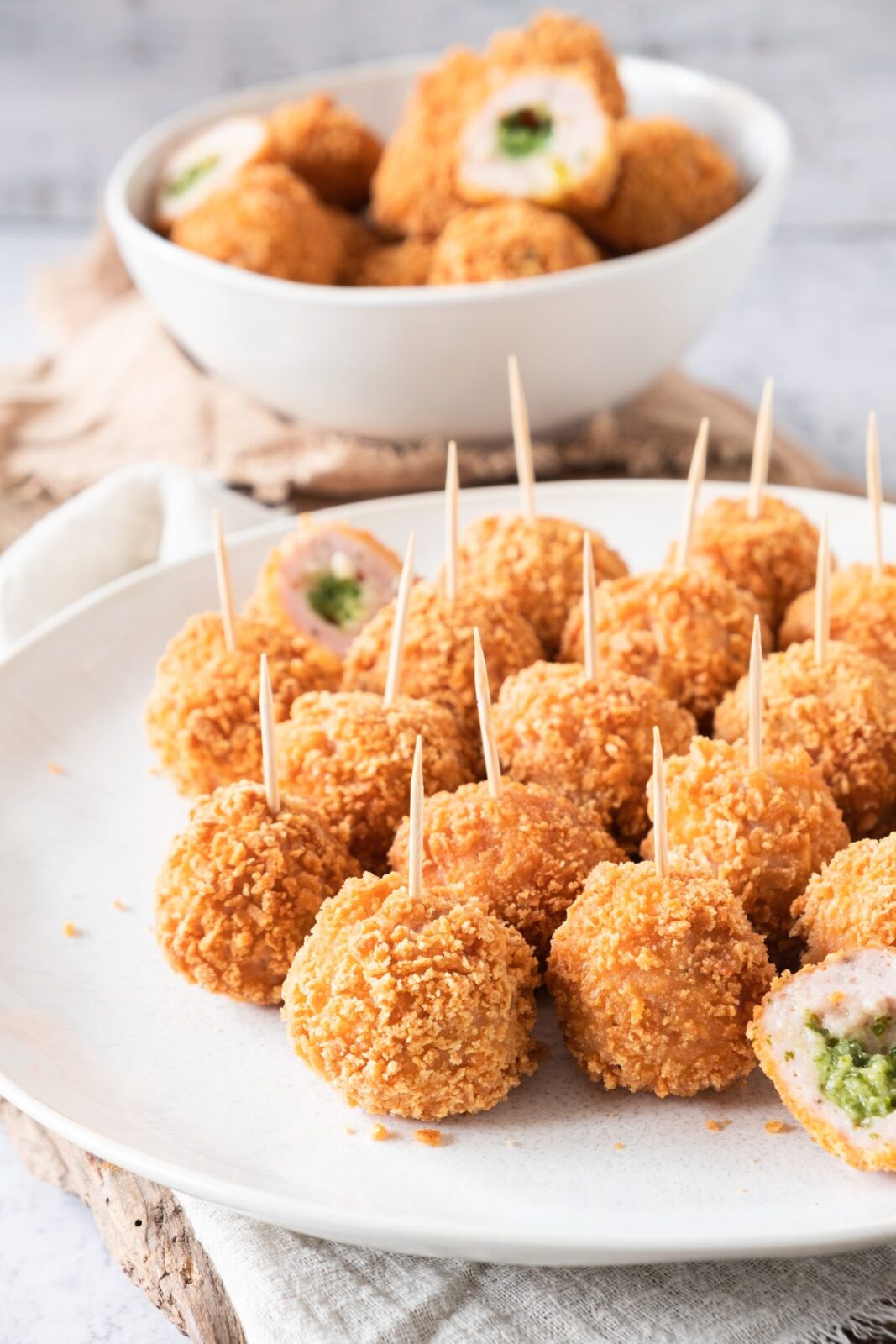 Platter of crispy garlic butter chicken balls on toothpicks with a serving bowl behind