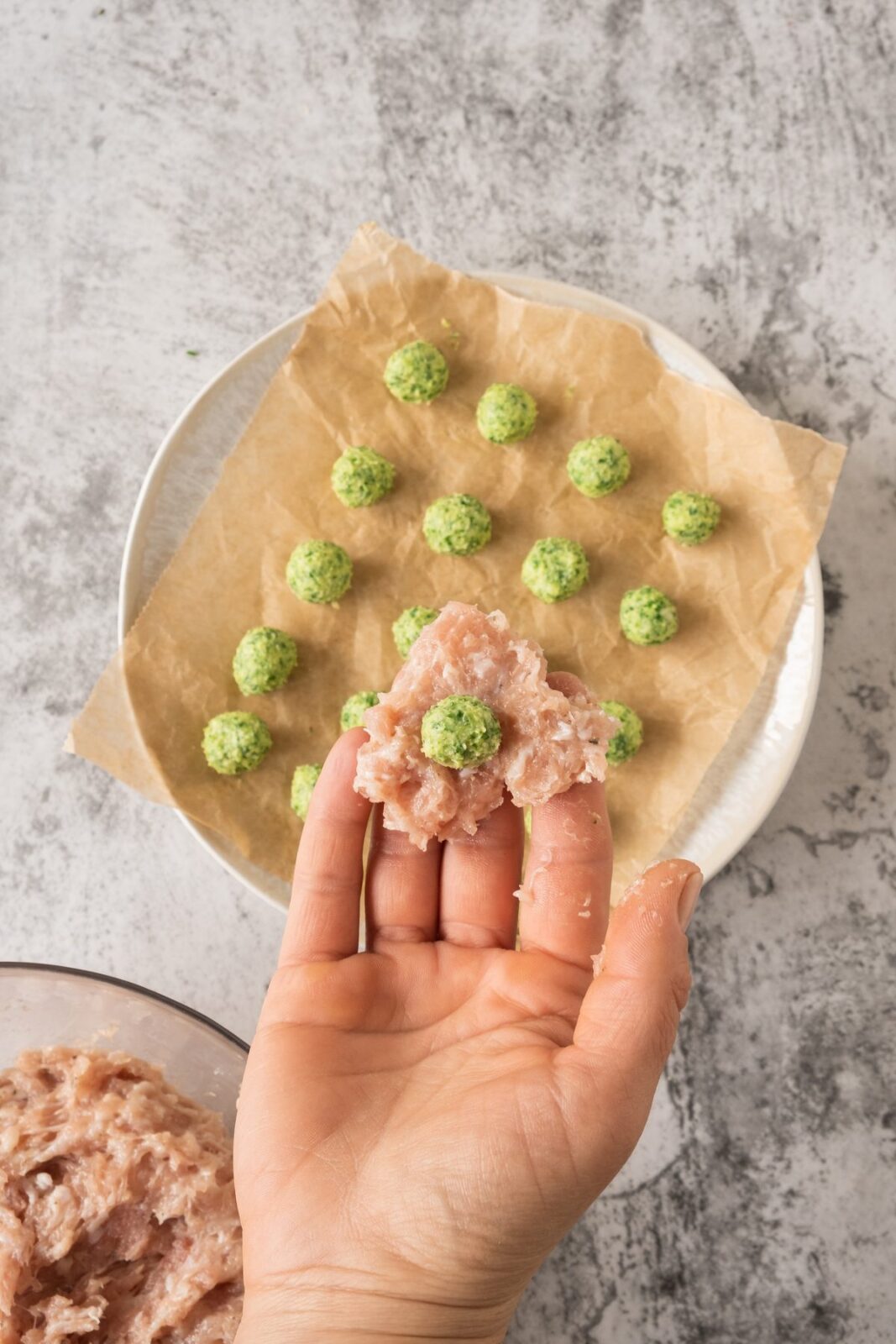 Wrapping seasoned ground chicken around a garlic butter ball by hand
