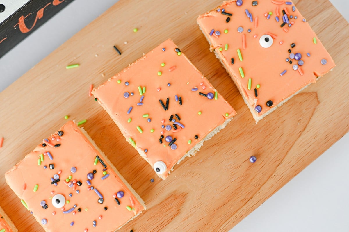 Halloween sugar cookie bars with orange frosting and spooky sprinkles cut into squares