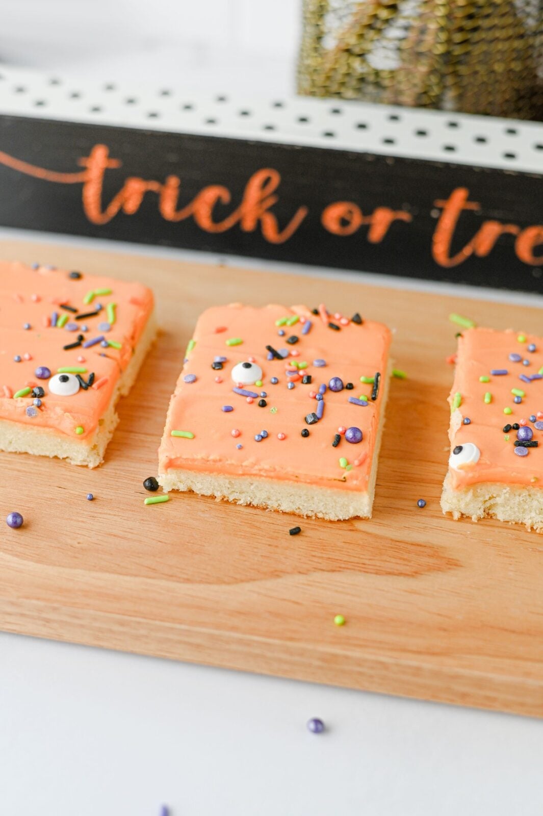 Frosted Halloween sugar cookie bars cut into squares on a wooden board