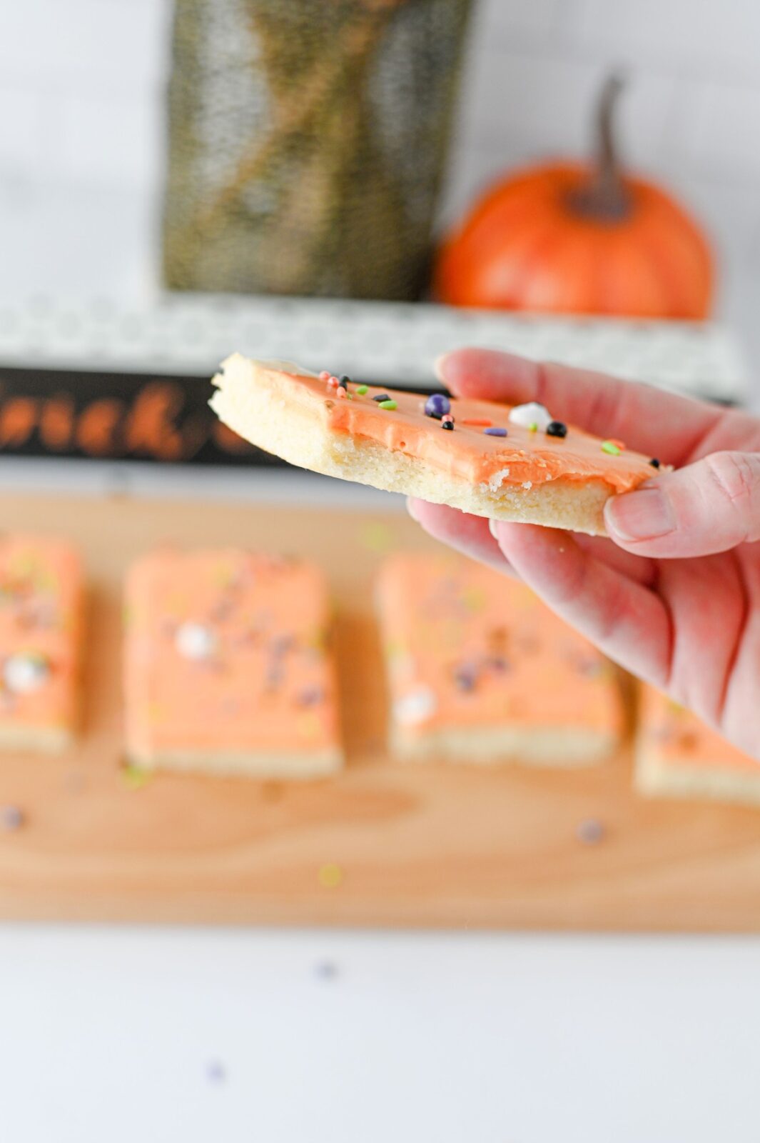 Hand holding a frosted Halloween sugar cookie bar showing the soft layers