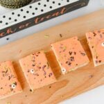 Halloween sugar cookie bars with orange frosting on a wooden serving board