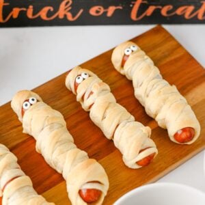 Mummy hot dogs with candy eyes in front of a trick or treat sign