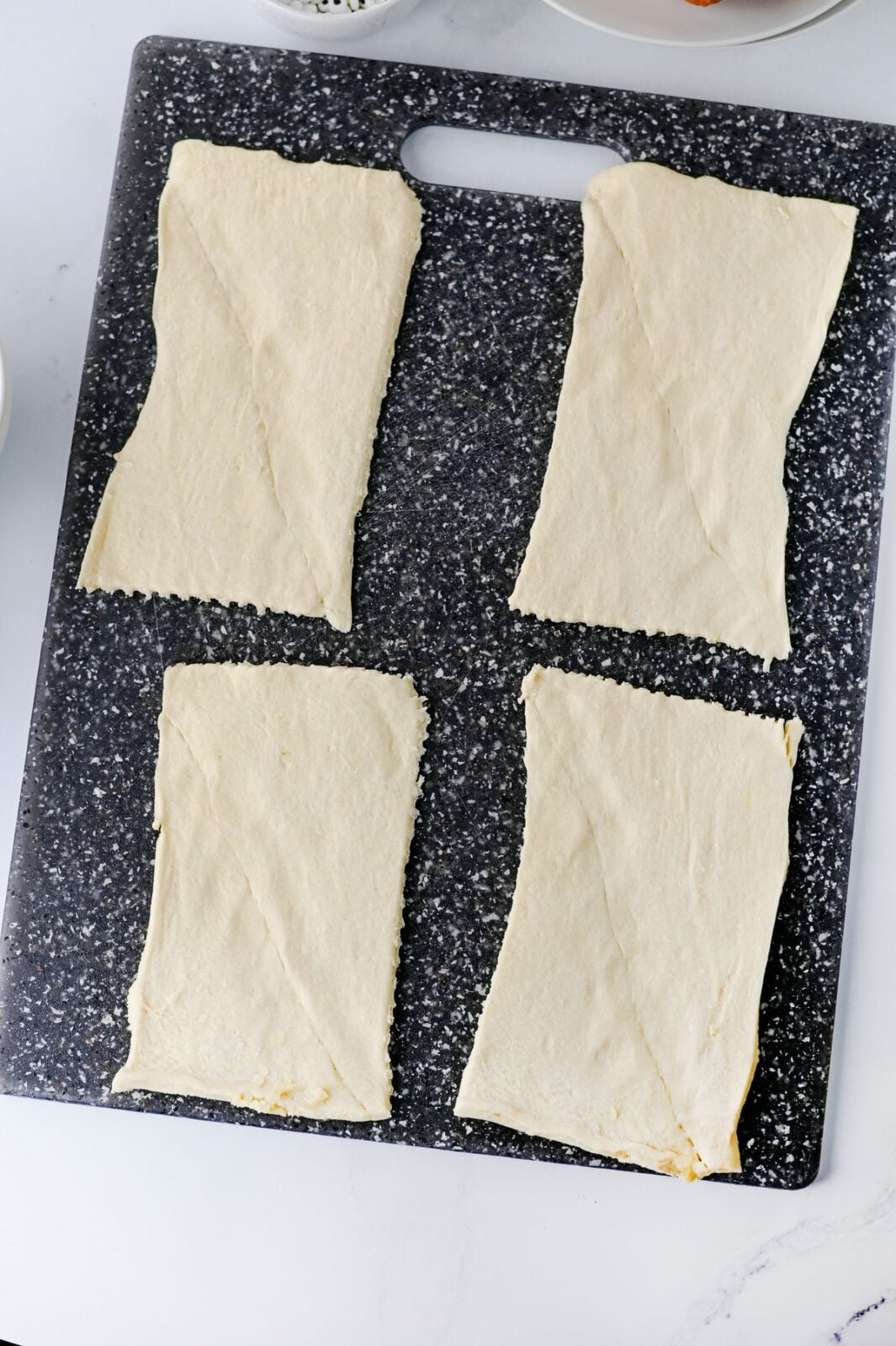 Crescent roll dough separated into four rectangles on a cutting board