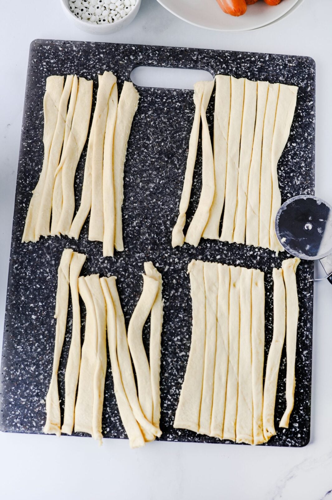 Slicing crescent dough rectangles into thin strips with a pizza cutter