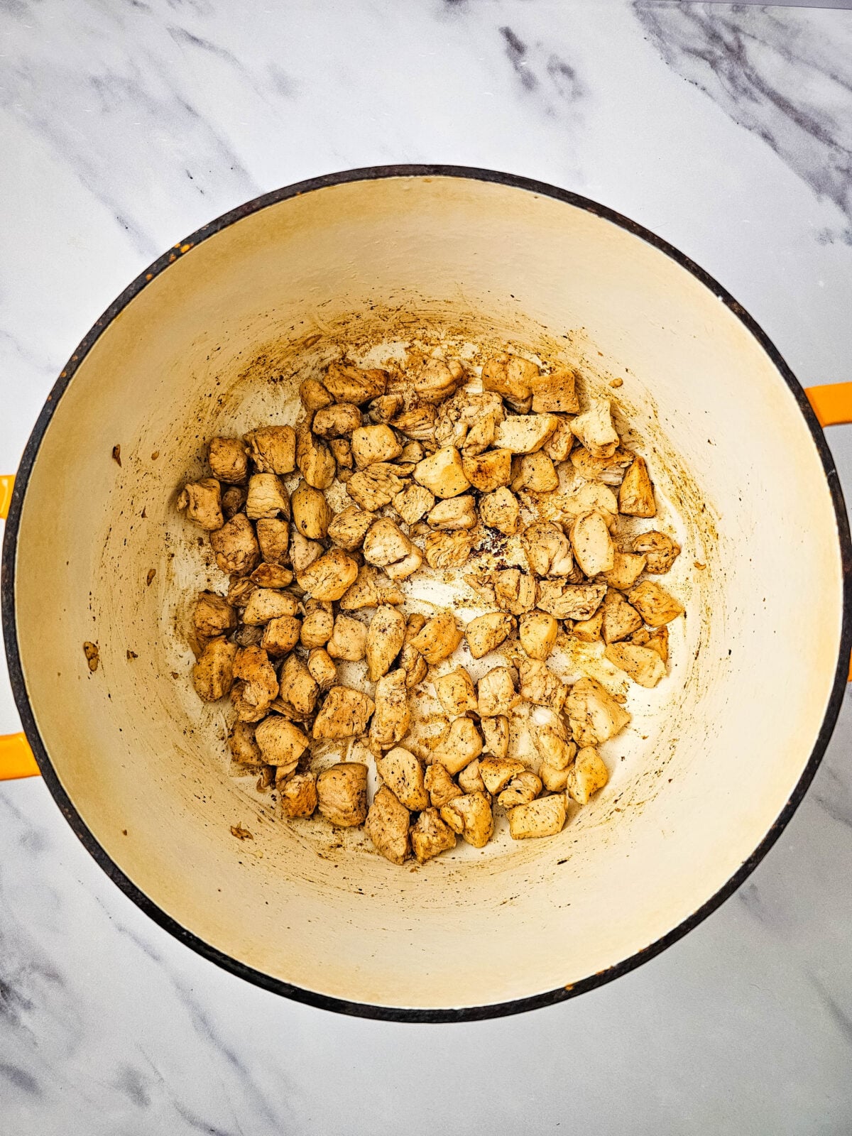 Seasoned chicken cooking in a Dutch oven