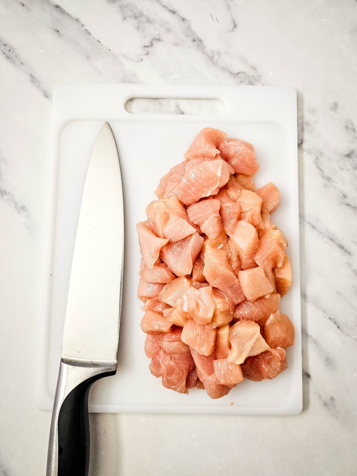 Cubed raw chicken breast on a cutting board