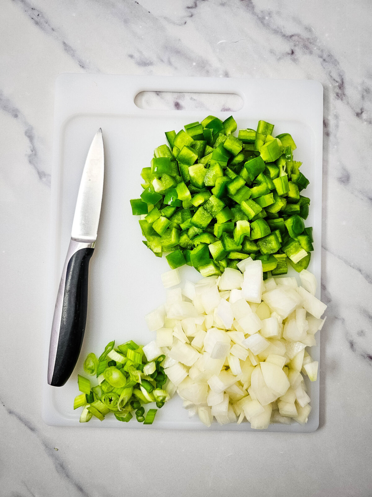 Diced onion and green bell pepper on a cutting board