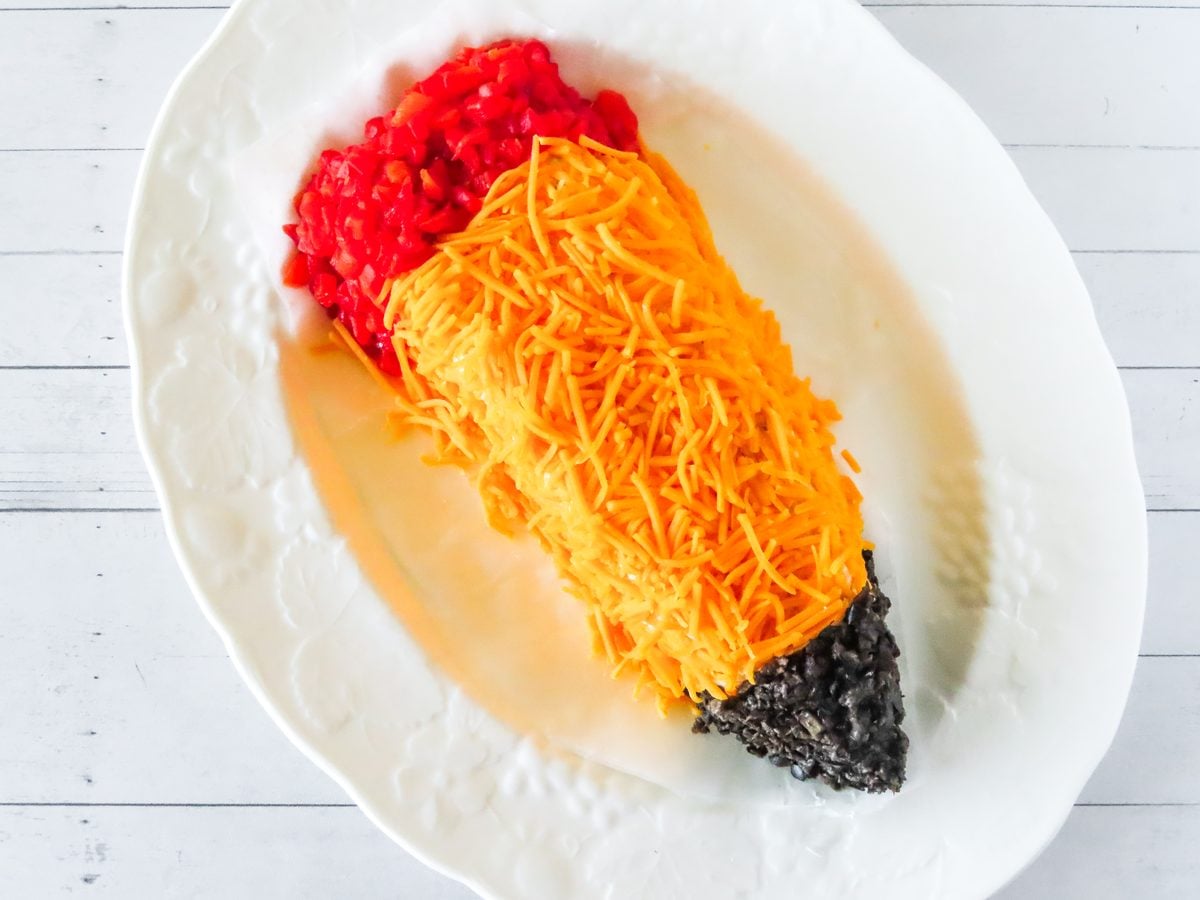 Cheddar coated pencil cheese ball with pimiento eraser and olive tip