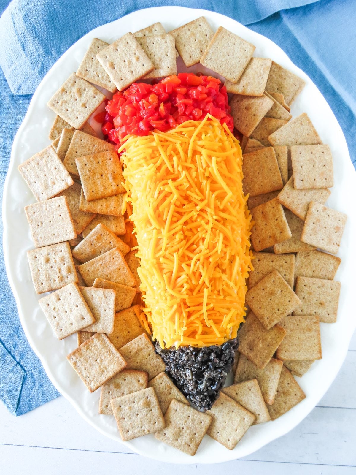 Pencil cheese ball surrounded by wheat crackers on an oval platter