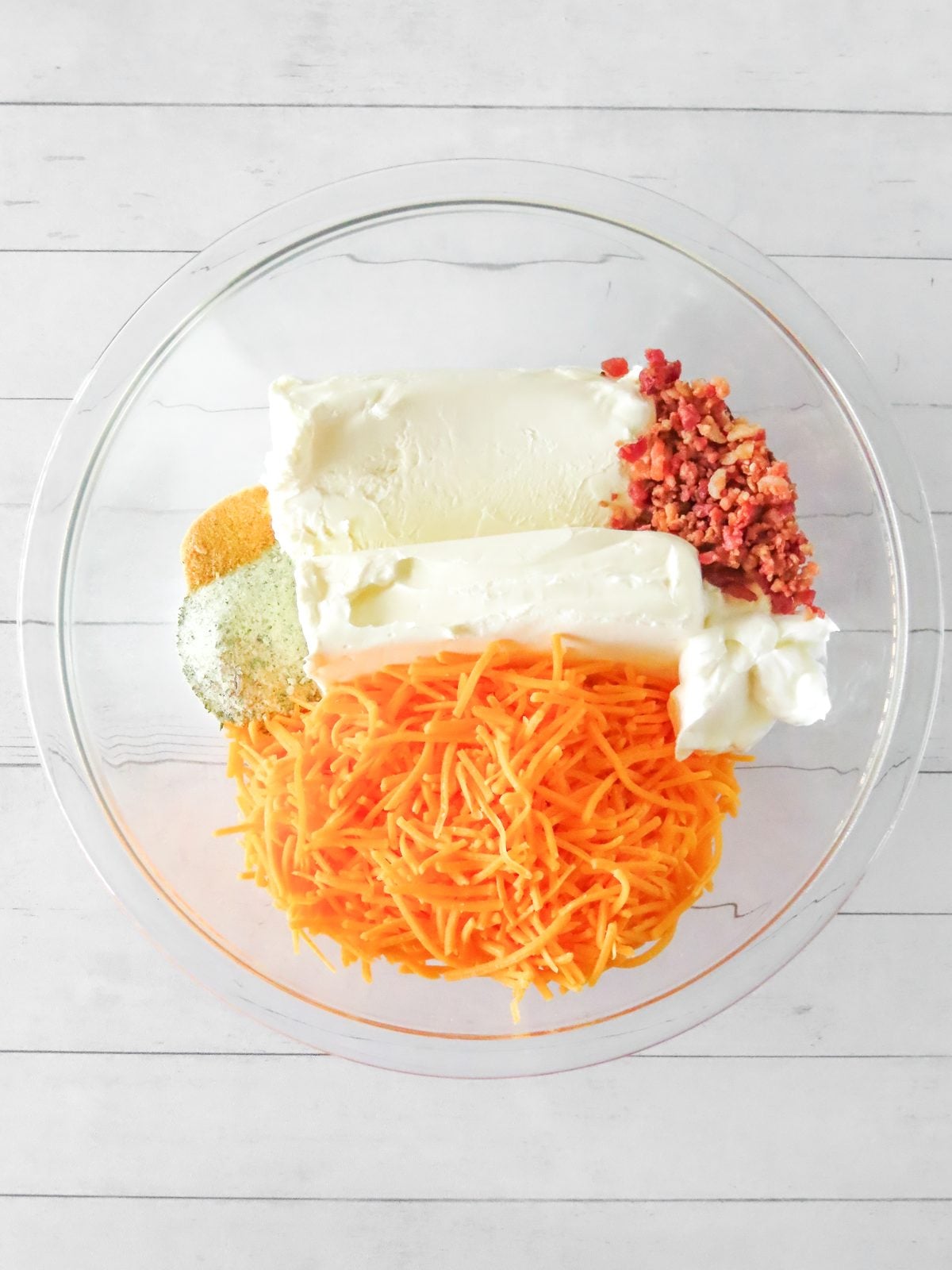 Cream cheese, shredded cheddar, sour cream, bacon bits, and ranch seasoning in a mixing bowl