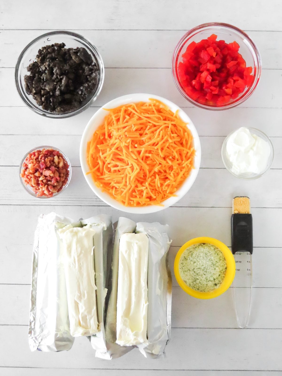 Pencil cheese ball ingredients: cream cheese, shredded cheddar, black olives, pimientos, bacon bits, sour cream, and ranch seasoning