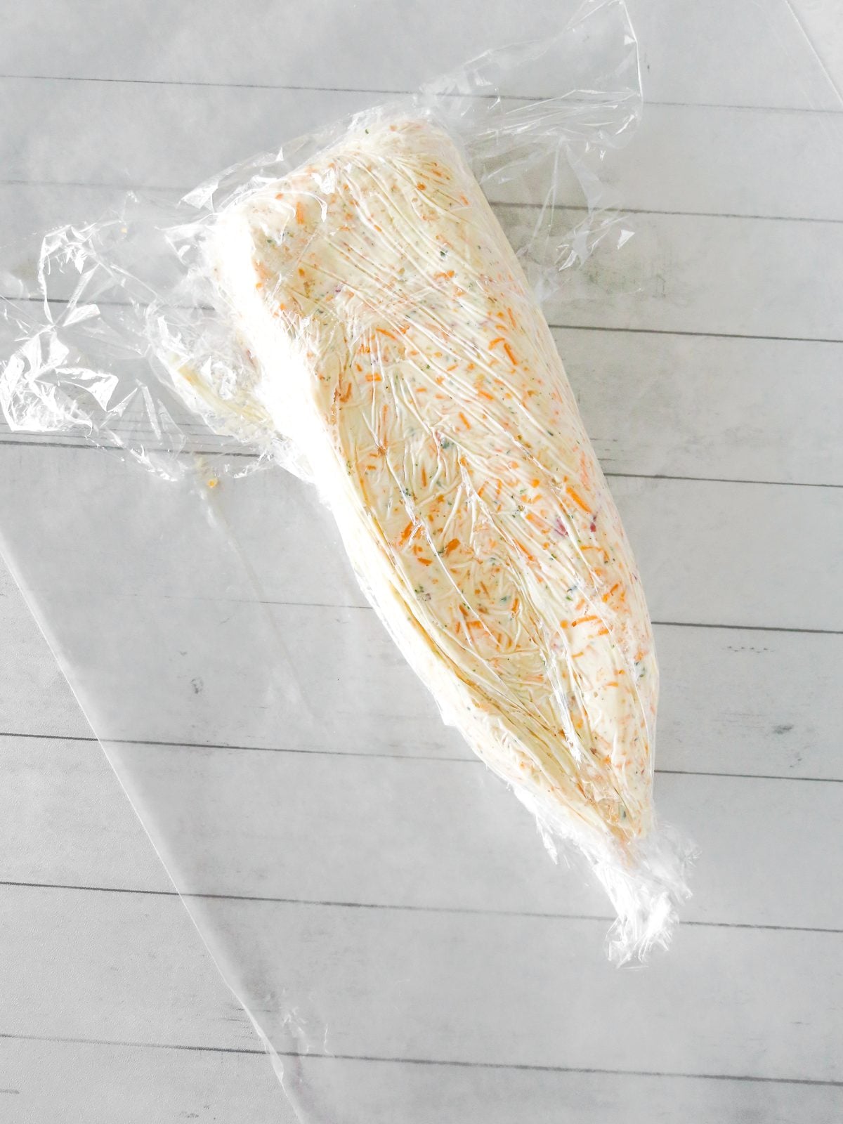 Cheese mixture molded into a pencil shape in plastic wrap
