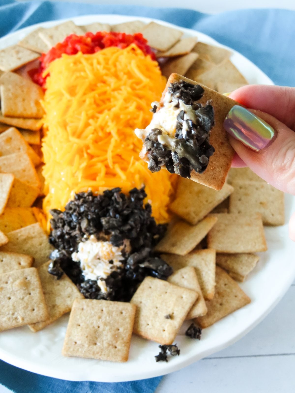 Scooping the pencil cheese ball with a wheat cracker