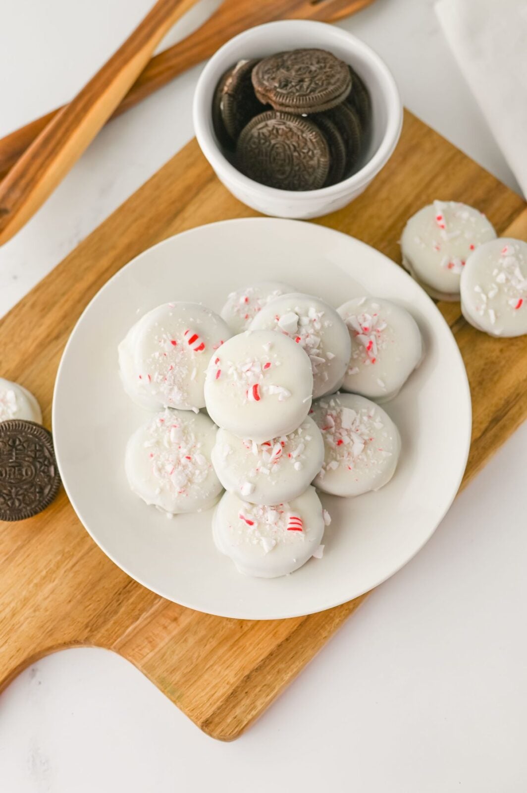Peppermint crunch Oreos served on a white plate on a wooden cutting board