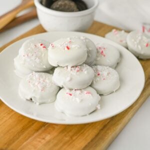 White chocolate dipped peppermint crunch Oreos piled on a white plate