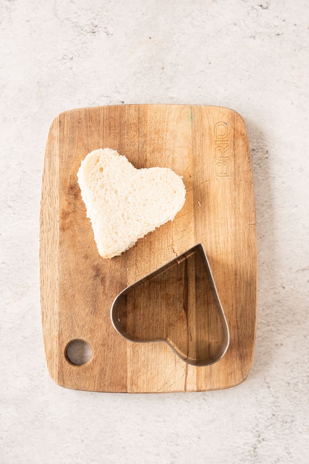 Heart shaped white bread cut with a cookie cutter on a wooden board