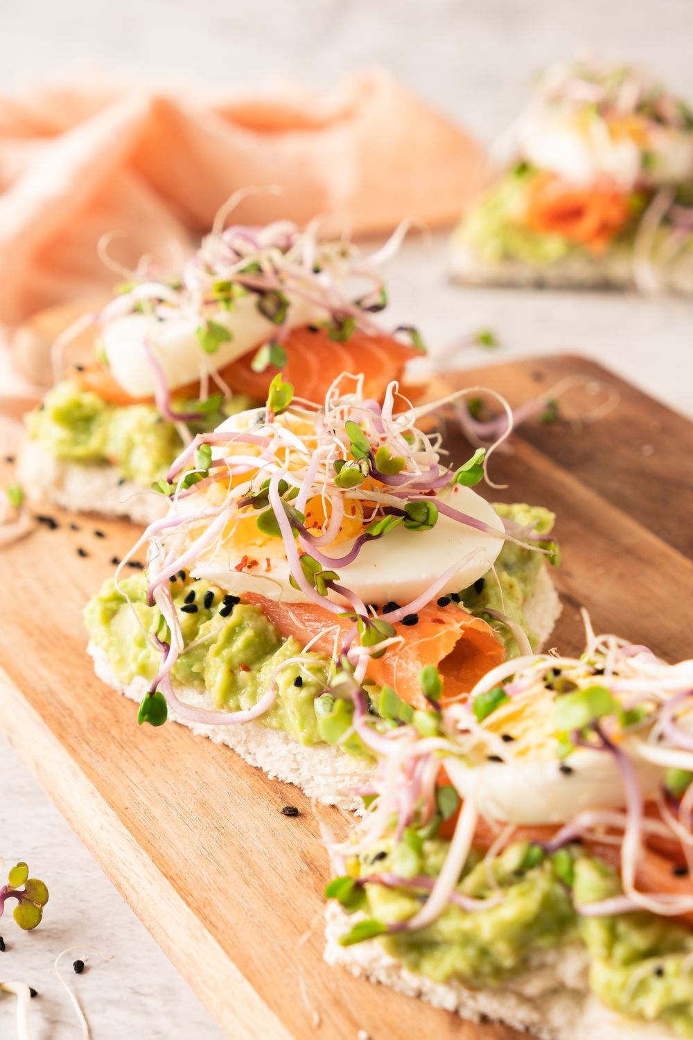 Smoked salmon avocado tea sandwiches served on a wooden board