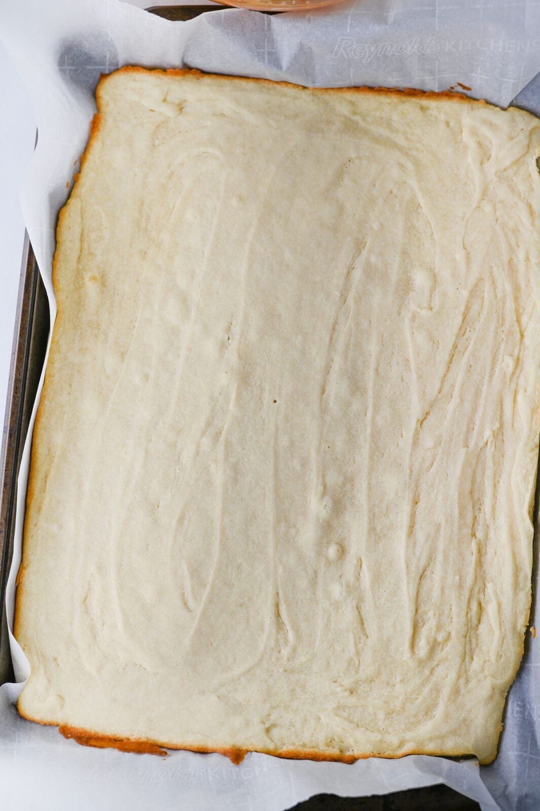 Baked sugar cookie bars with golden edges cooling in the pan