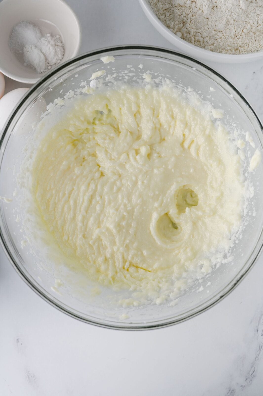 Butter, oil, and sugars creamed together in a glass mixing bowl