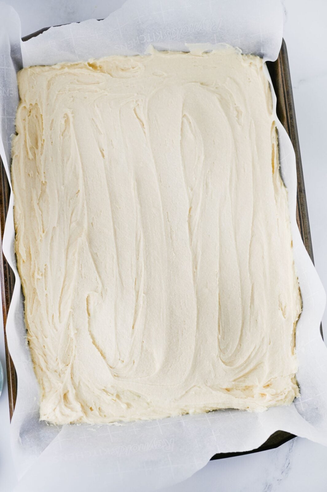 Sugar cookie dough spread evenly on a parchment lined sheet pan