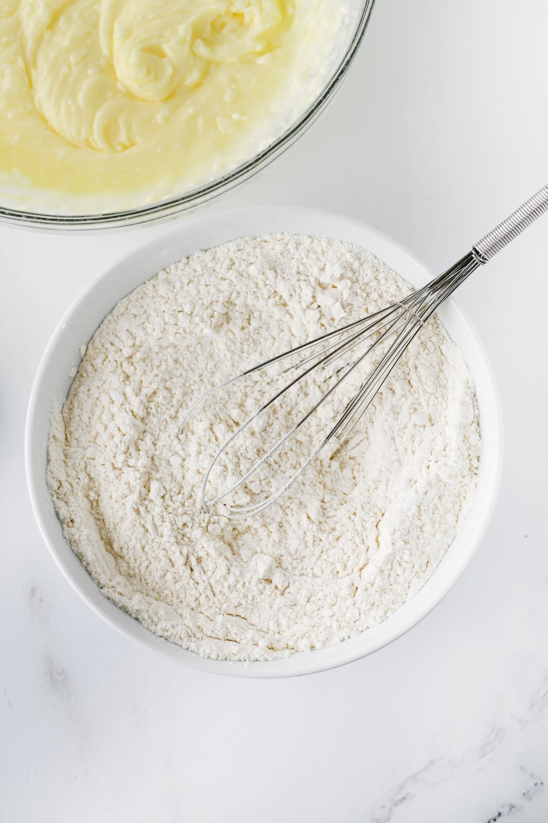 Flour, baking powder, cream of tartar, and salt whisked together in a white bowl