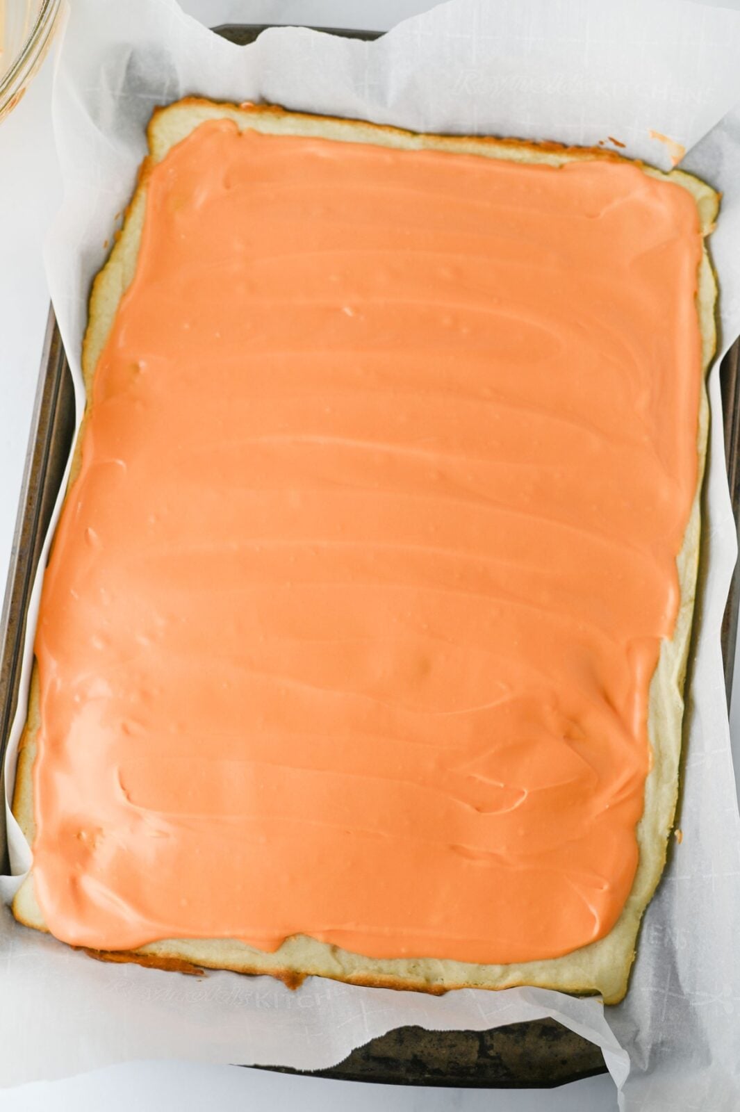 Orange frosting poured and smoothed over the cooled cookie bars