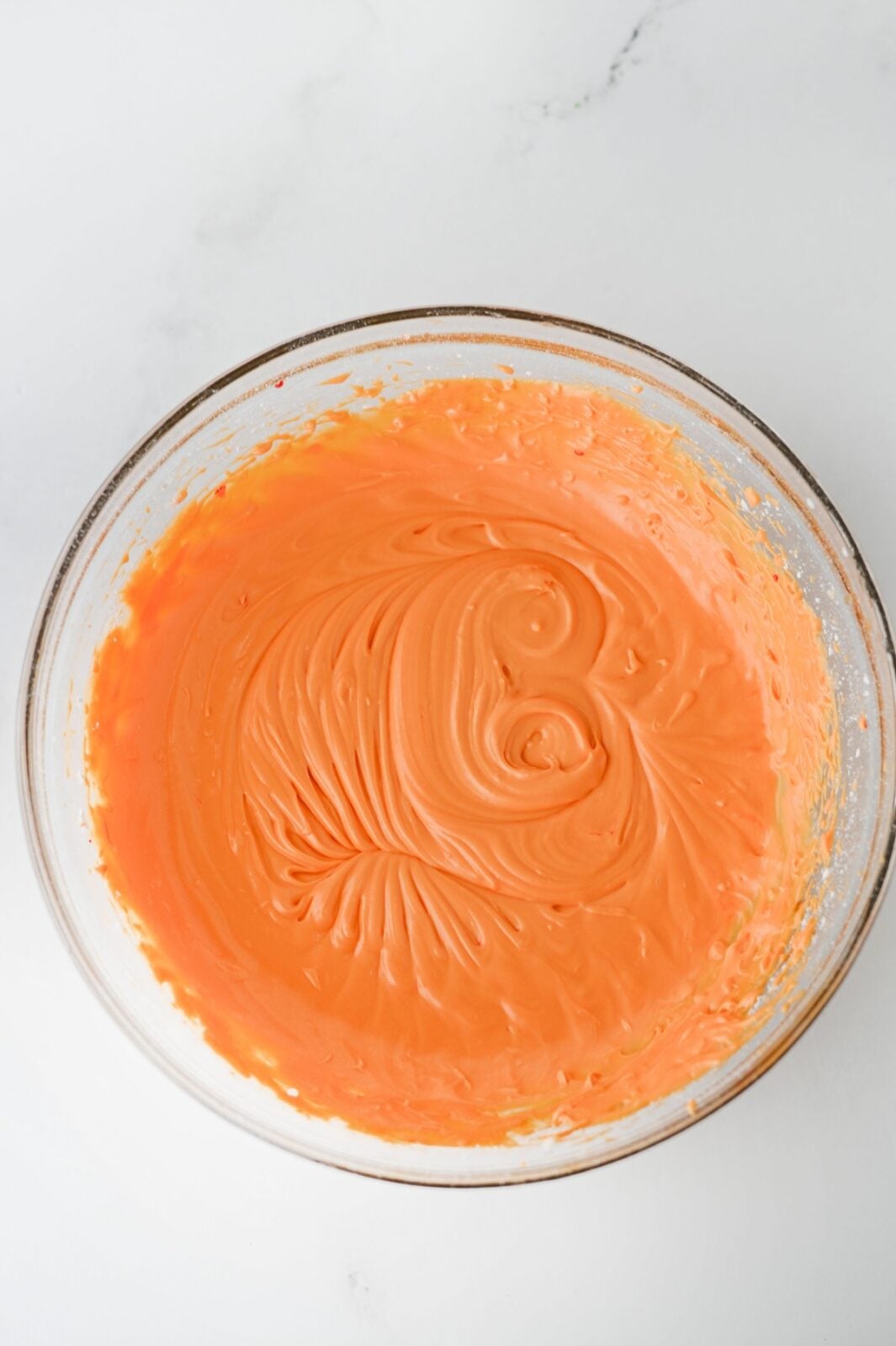 Orange sour cream frosting mixed in a glass bowl