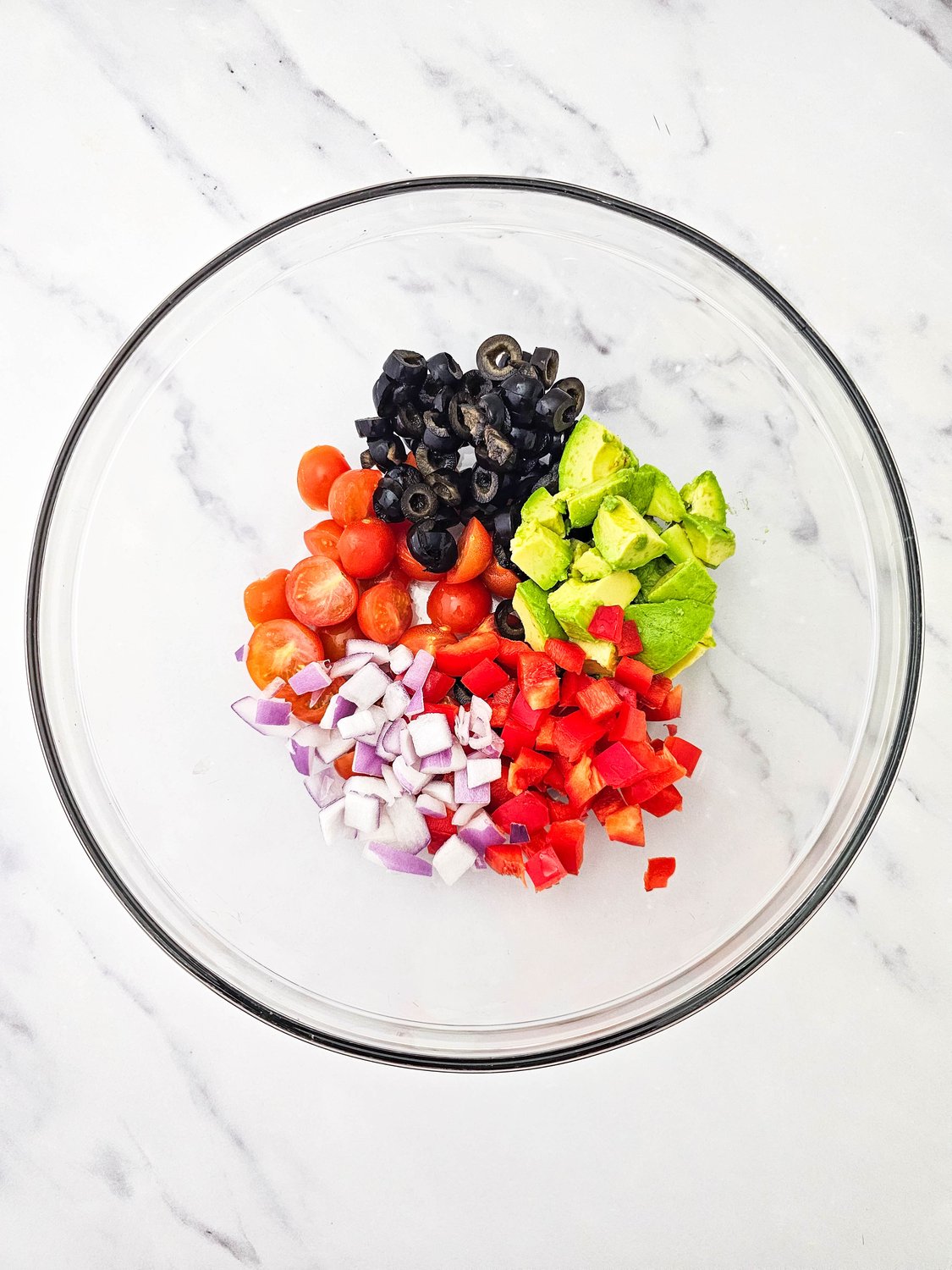 Chopped vegetables for vegan pasta salad in a glass bowl
