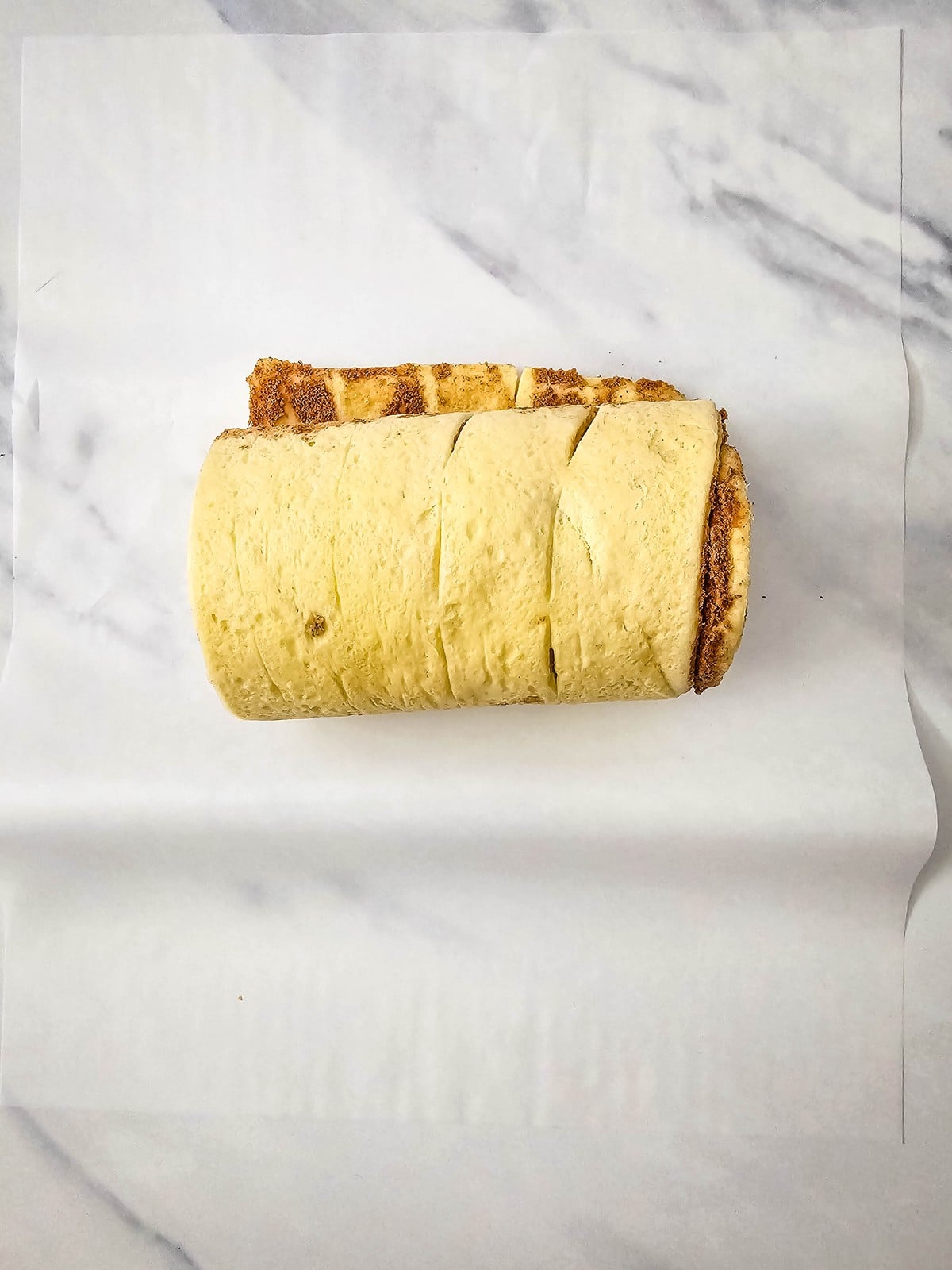Scored log of refrigerated cinnamon roll dough on parchment paper