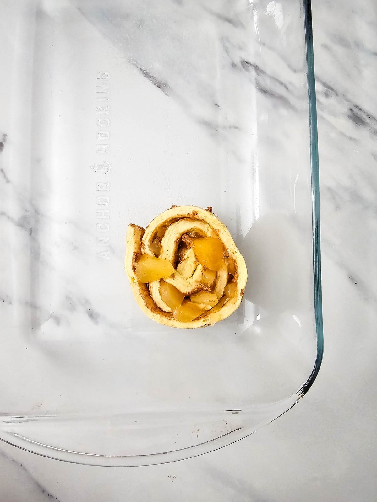 One re-rolled apple cinnamon roll in a greased glass baking dish